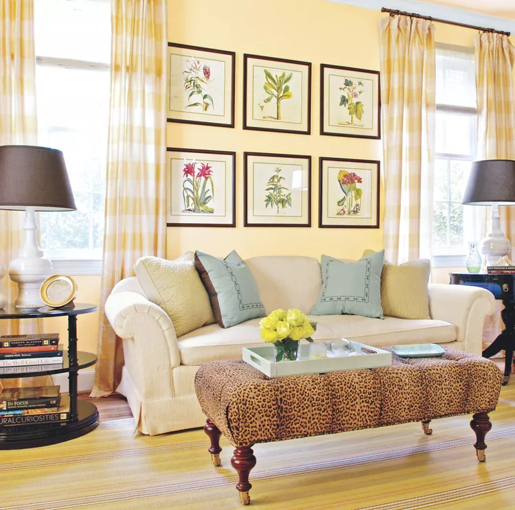 A butter yellow wall in the living room with light blue accent pillows and yellow checked curtains. The striped carpet is yellow and blue.