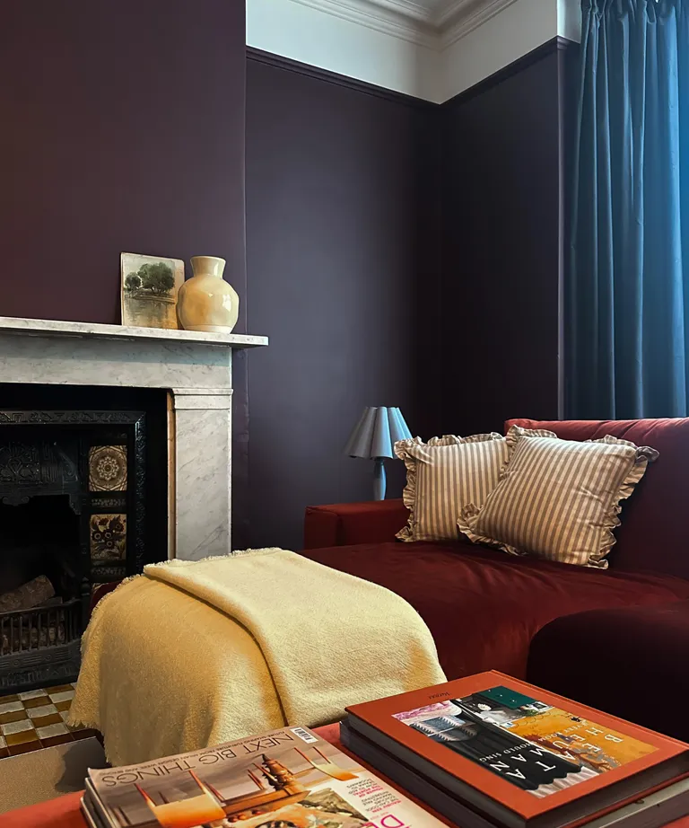 Moody navy blue walls with a settee covered in a butter yellow throw.