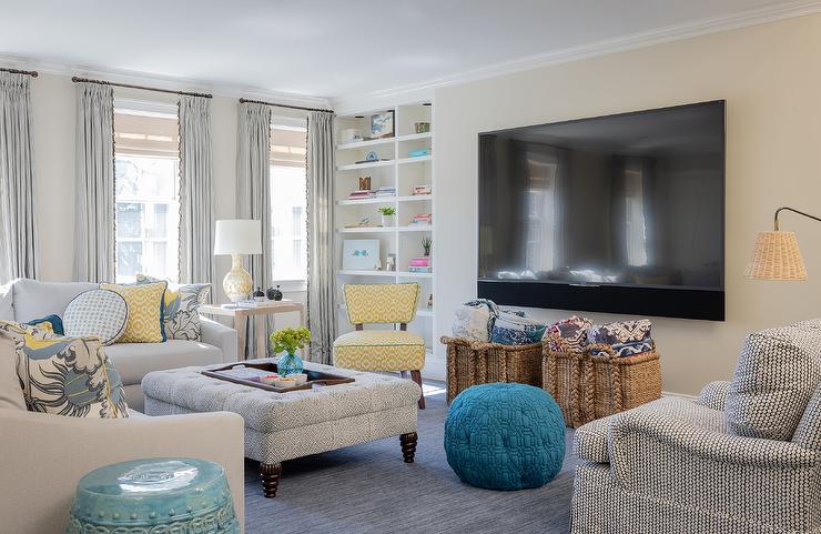 Yellow, cream and teal blue living room with muted accents. A yellow upholstered chair is a focal point in front of the built in bookshelves.