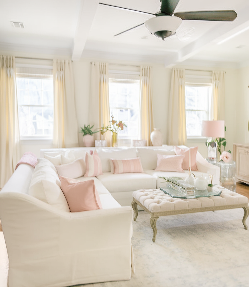 A mostly white and cream living room with pale pink accents.