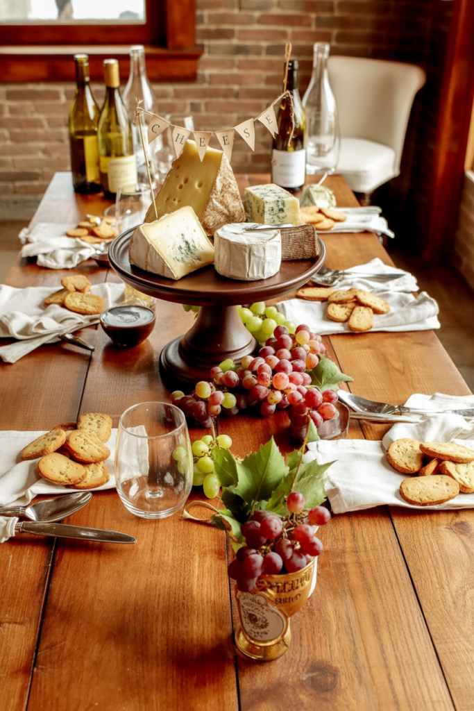 A tiered cheese board becomes the stunning focal point, decorated with a miniature "CHEESE" pennant banner strung between wine bottles